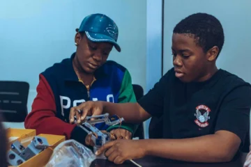 Two students assembling a robot in a hands-on STEM workshop in Accra, Ghana.