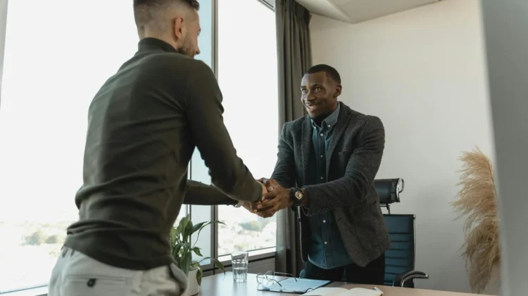 Two businessmen exchanging a handshake during a professional meeting in a modern office setting.