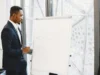 Confident businessman in a suit giving a presentation on growth strategy with a chart on a flipchart.