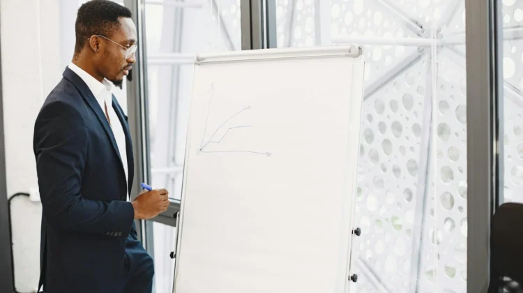 Confident businessman in a suit giving a presentation on growth strategy with a chart on a flipchart.