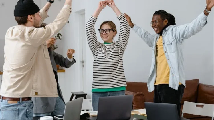 A multicultural group of professionals celebrating success in a modern office setting, emphasizing teamwork and collaboration.