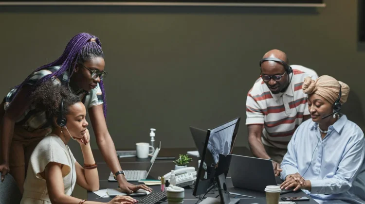A diverse team of professionals collaborating in a modern office environment, using headsets and computers.