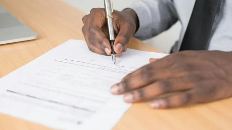 Close-up of a businessman signing a contract at an office desk.